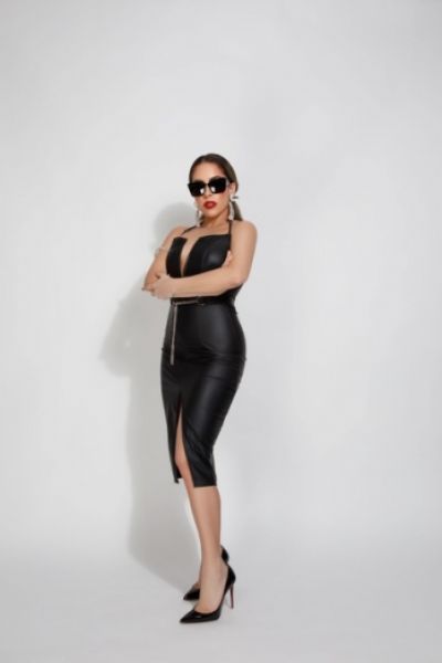 Full length photo of Juniper dressed in a black dress and wearing dark sunglasses 