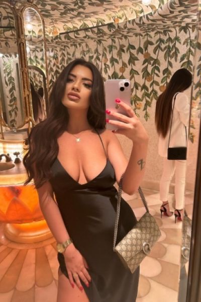Mirror selfie of Hailey in a low cut black dress 