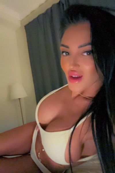 Busty brunette escort Elizabeth laying on her bed in a yellow underwear set 