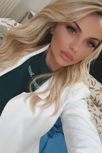 A picture of a very pretty blonde lady wearing a white blazer over a black top 