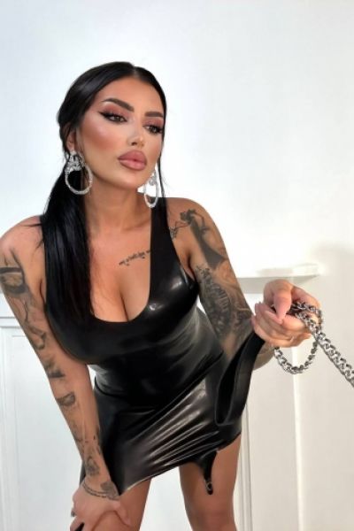 Tattooed dominatrix in a black latex dress 