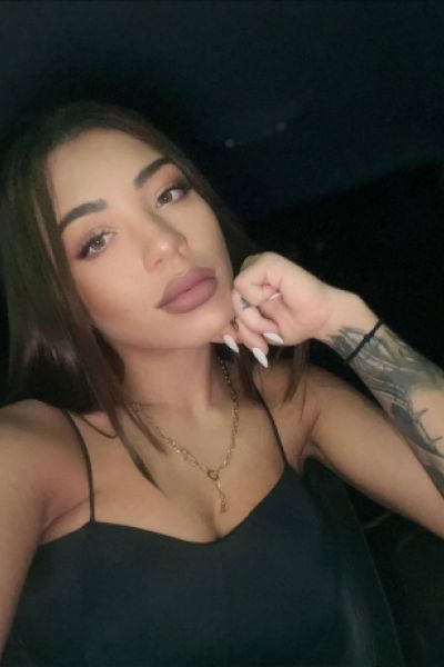 A close up selfie of a very sexy brunette escort showing off her tattoos 
