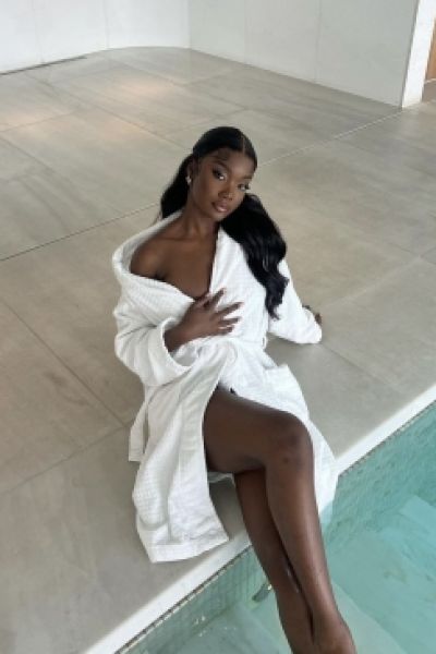 A sexy ebony escort sat by a pool in her robe 