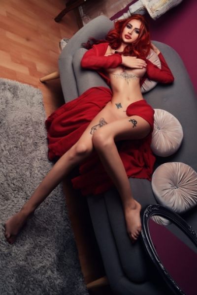 Slim Pune escort Anika laying on her sofa with her arm covering her boobs 